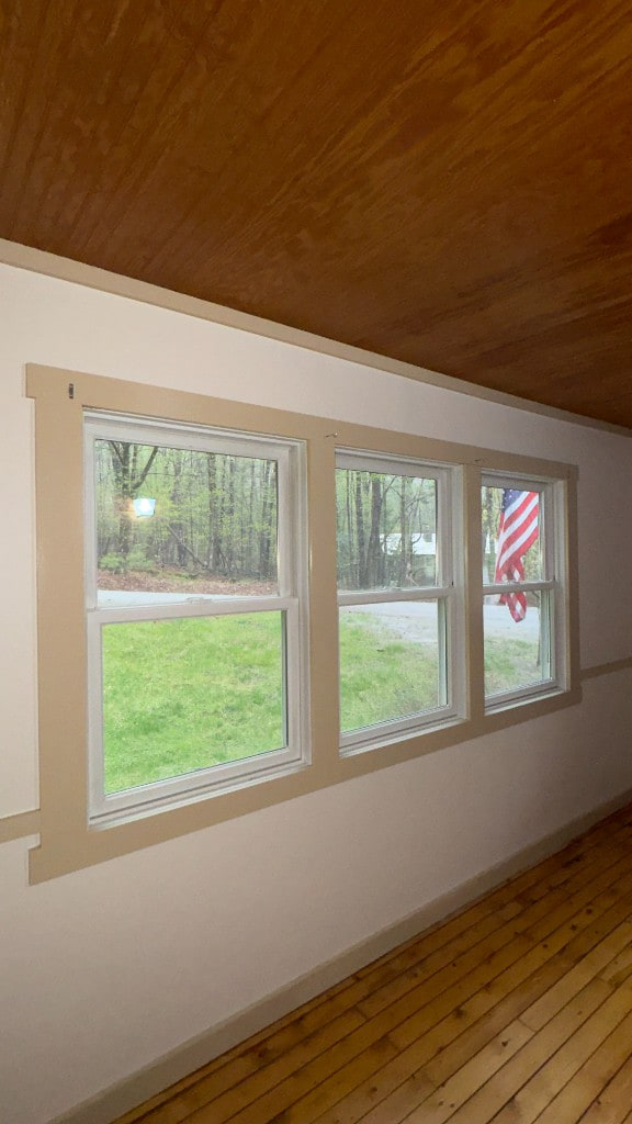 Three white-trimmed windows with tan casing overlooking a green yard
