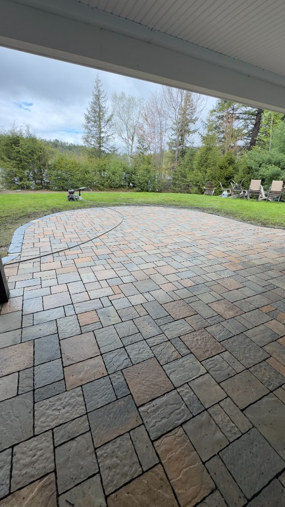Wide stone paver patio overlooking a green backyard