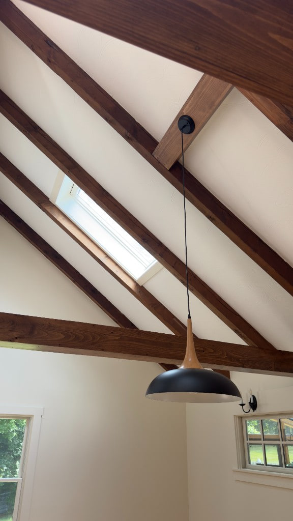 Vaulted white ceiling with dark stained wood beams and pendant light