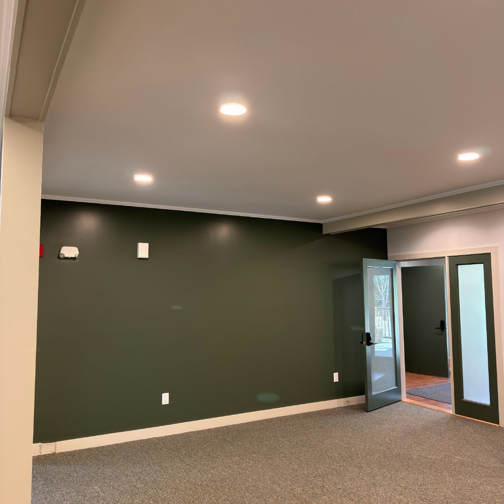Forest green accent wall with white ceiling and recessed lighting