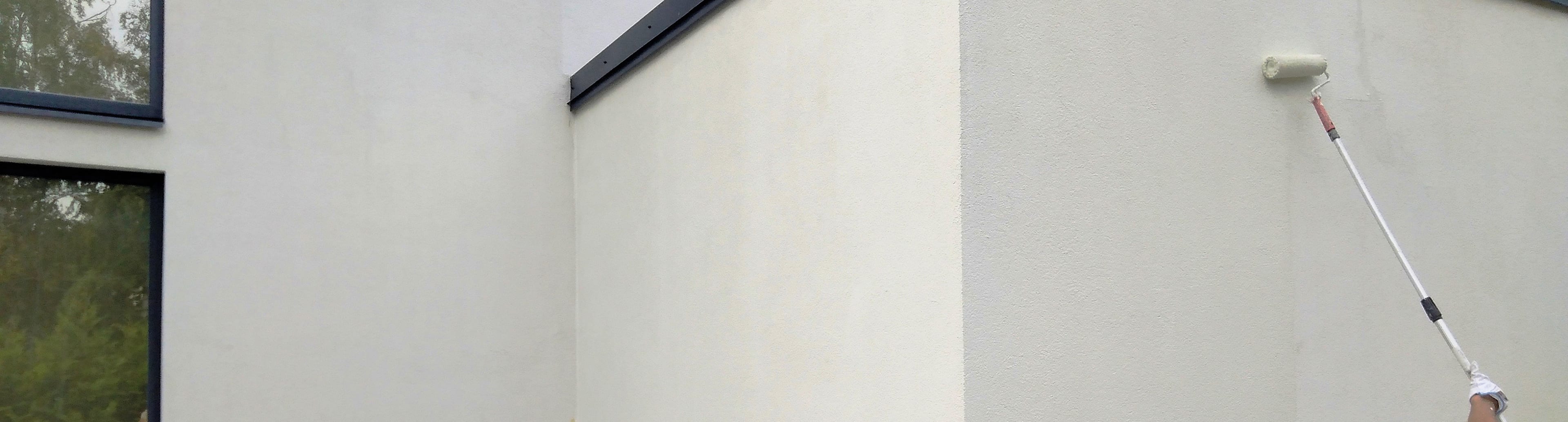 Rolling fresh paint onto an exterior wall