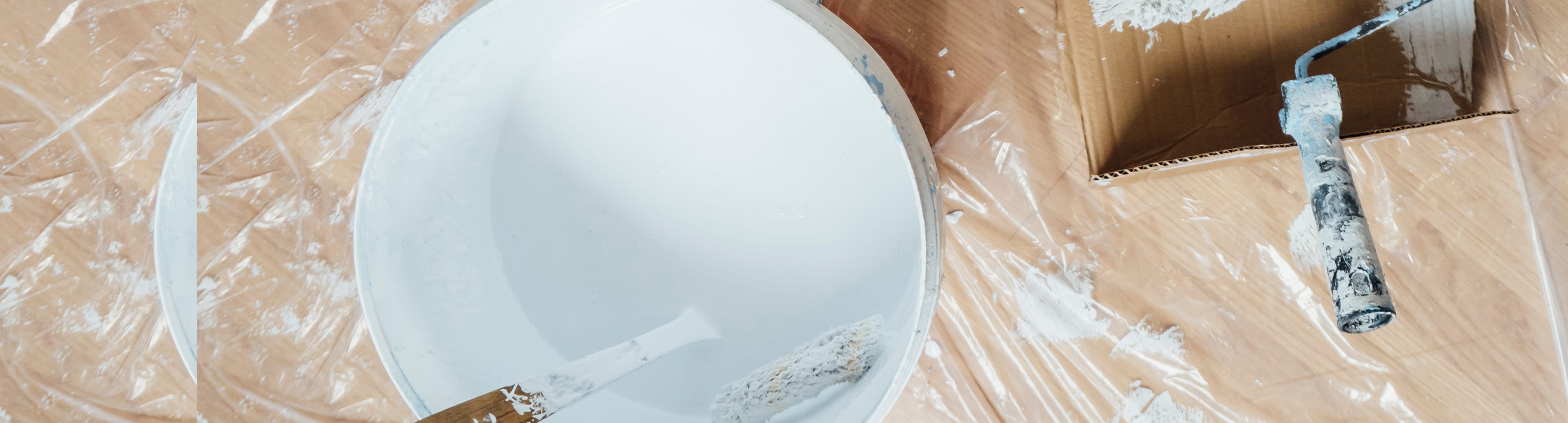 Paint bucket and roller frame on a drop cloth during an interior paint job