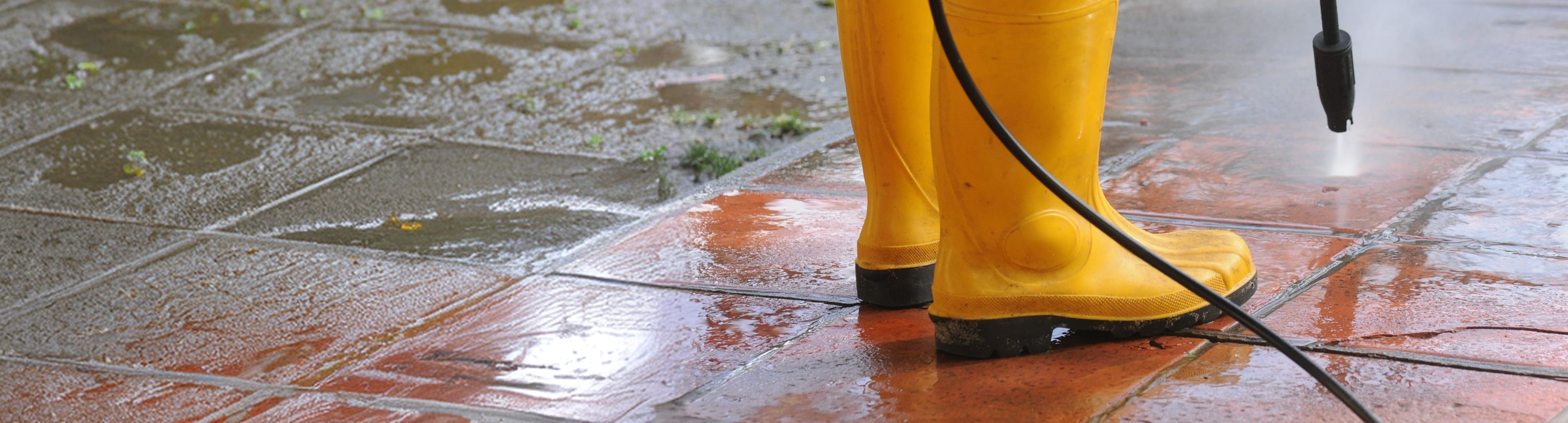 Yellow boots and a pressure washer cleaning a patio