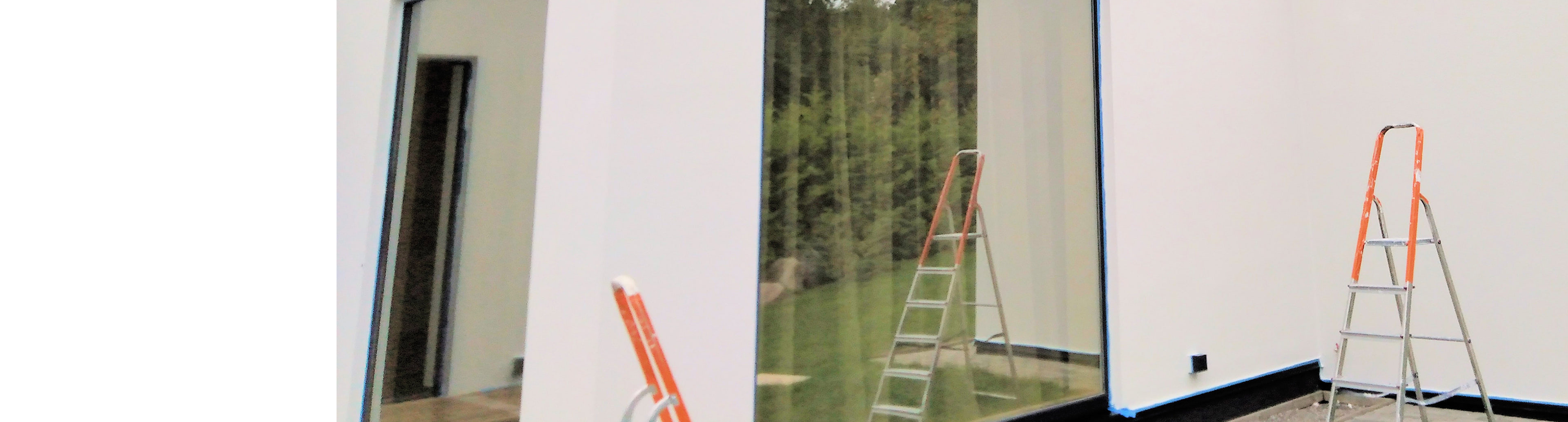 Ladders against a white house during exterior paint prep