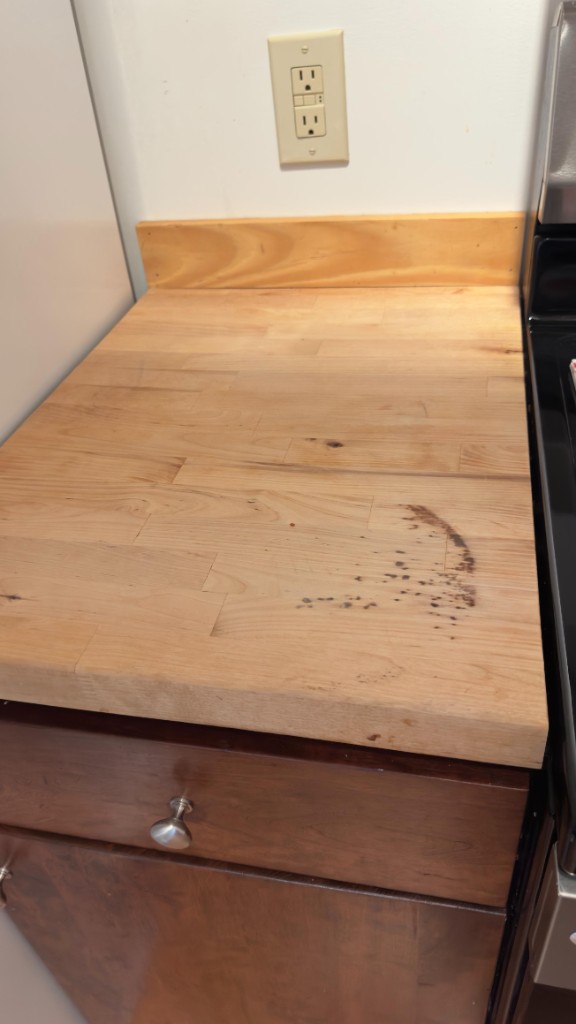 Butcher-block kitchen counter with a dark stain before refinishing