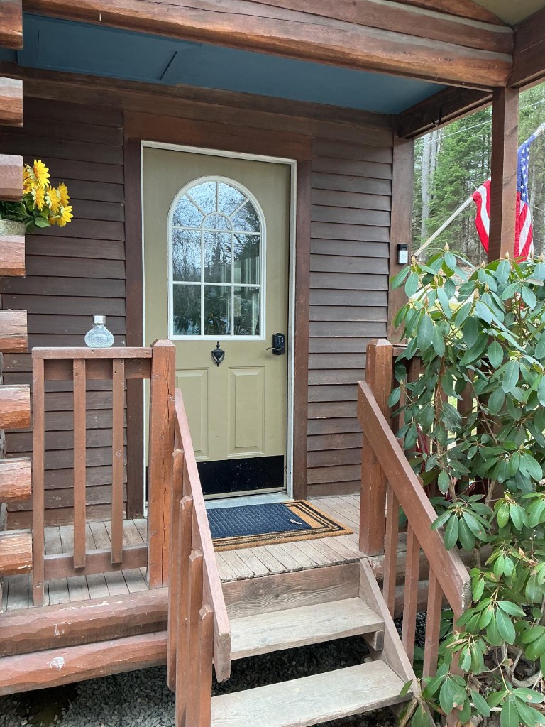 Cabin entry with sage door and natural wood porch before staining