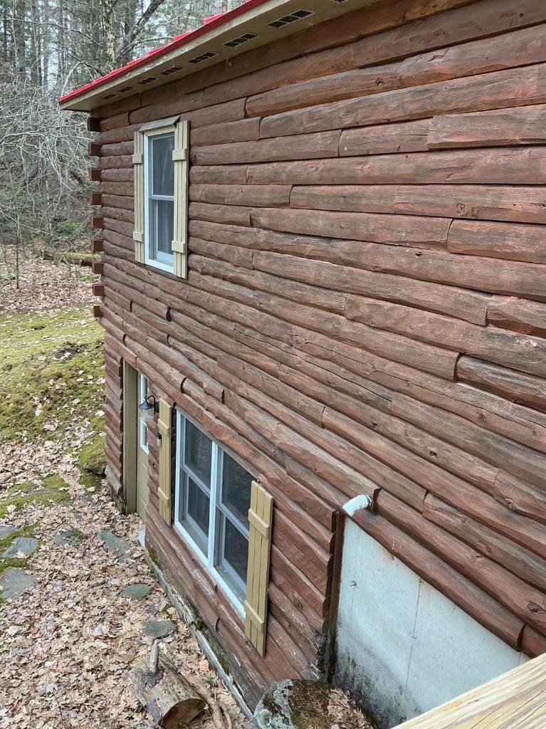Two-story log home with faded stain before exterior refinishing
