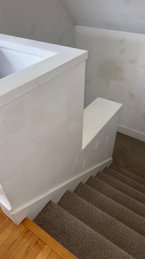 Stair landing half-wall with filler patches before painting